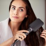 Woman using a hair straightener for sleek, smooth hair styling at home in a relaxed setting